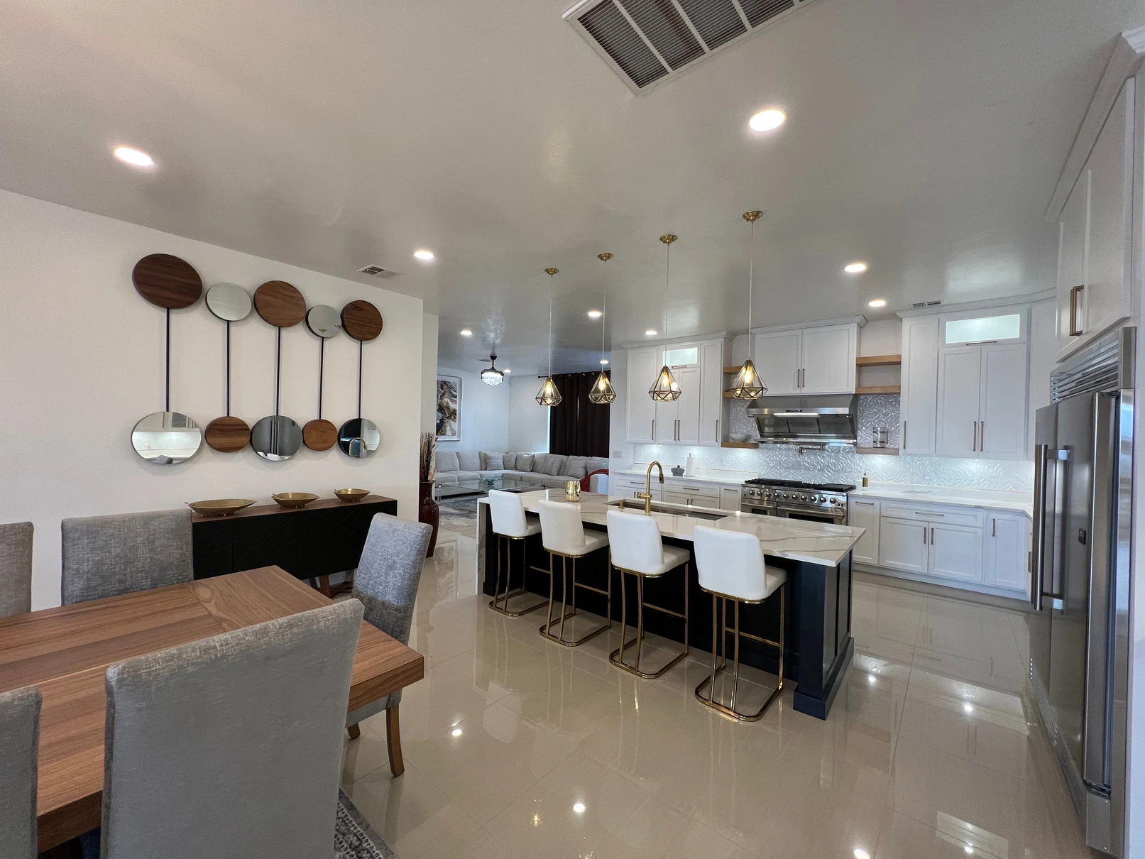 Custom white cabinetry and a black kitchen island with warm brass accents by Concept Cabinets