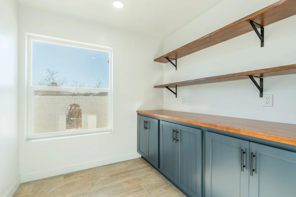 Blue pantry cabinetry with a wood counter and floating shelves