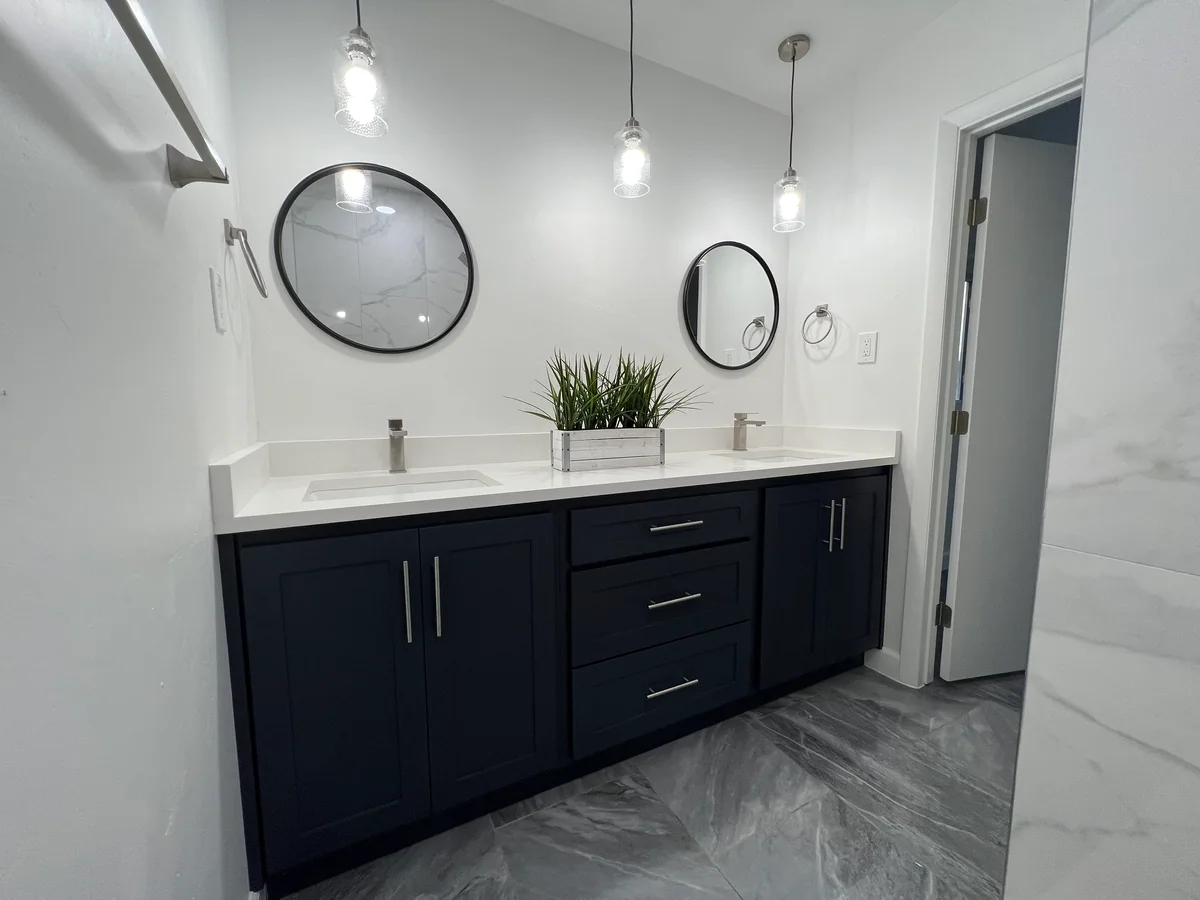 Dark double vanity beneath round mirrors