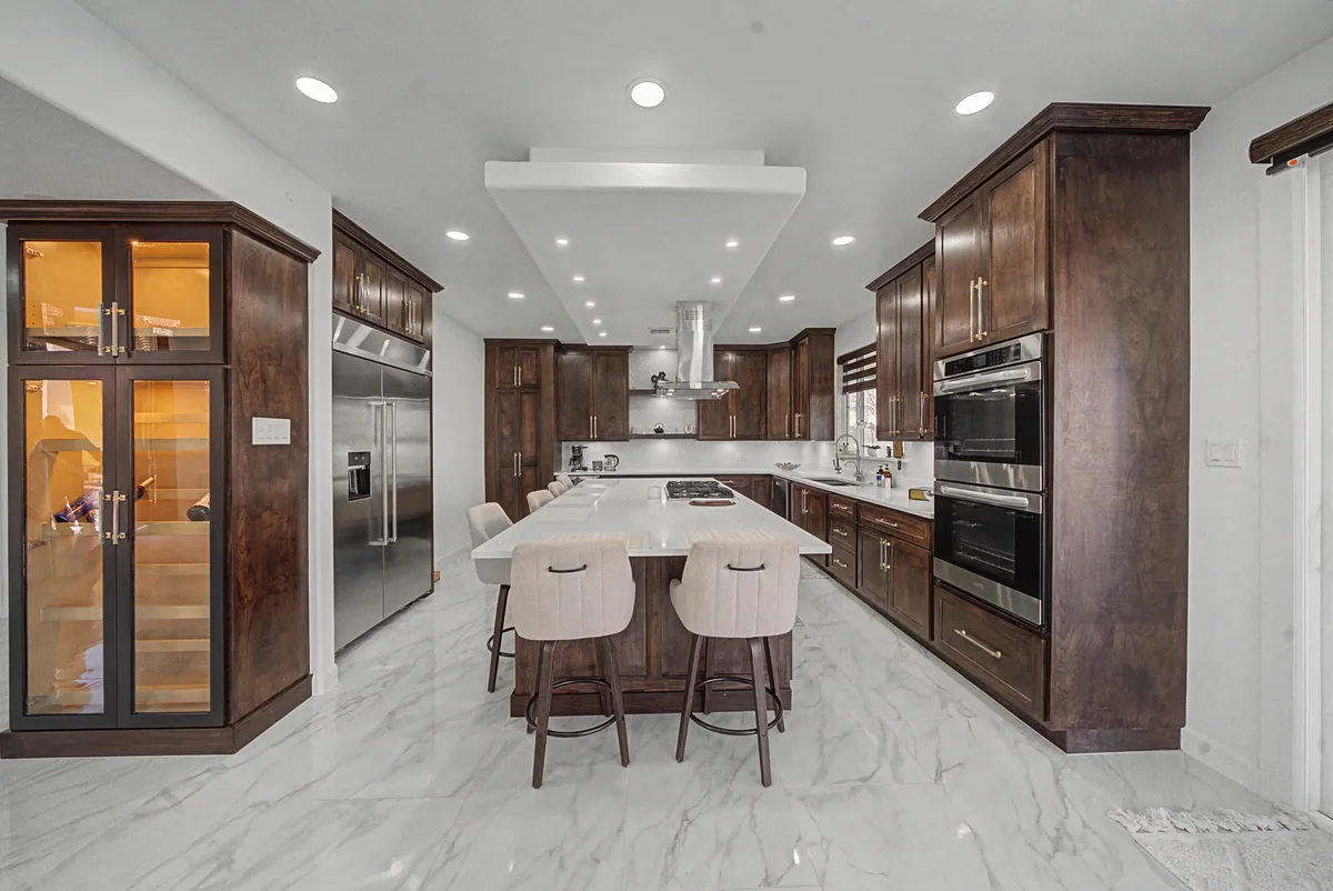 Warm Heritage kitchen with wood cabinetry, lighted glass cabinets, view 1